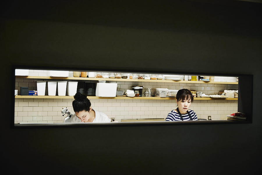 Two female chefs preparing for evening meal service in restaurant kitchen Photograph by Thomas Barwick