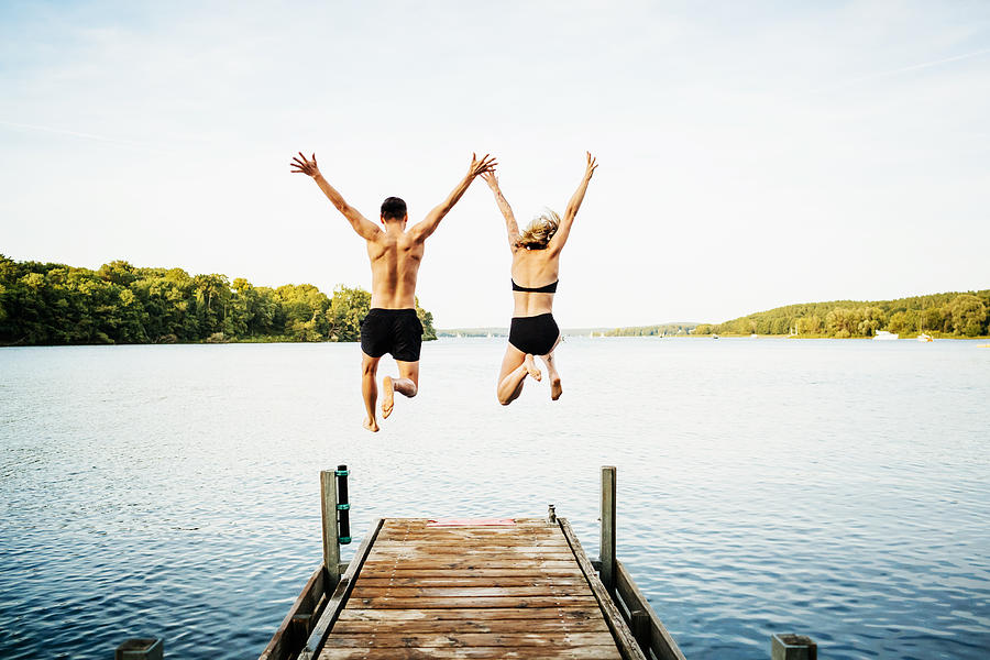 Two Friends Jumping Off Jetty At Lake Together Photograph by TommL Two Friends Jumping Off Jetty At Lake Together Photograph by TommL