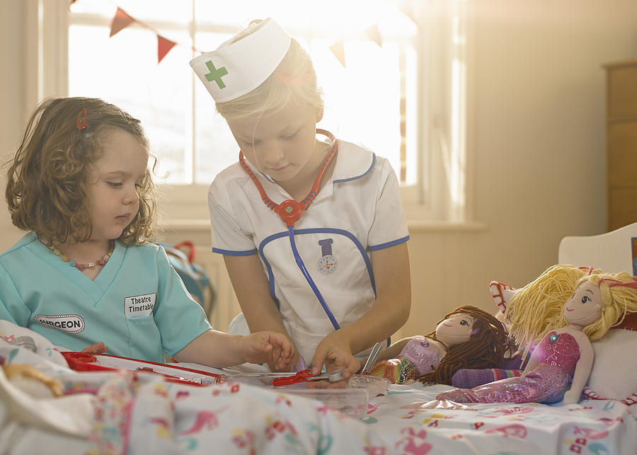 Two girls playing, dressed as doctor and nurse Photograph by 10000 Hours