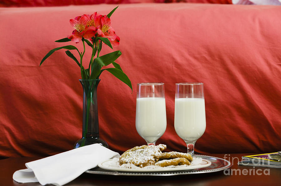 Two glasses of milk and flowers at the foot of a hotel bed. Photograph by Don Landwehrle