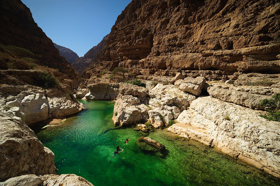 Two people swimming in the turqoise waters of Wadi Shab, Oman Photograph by by Marc Guitard
