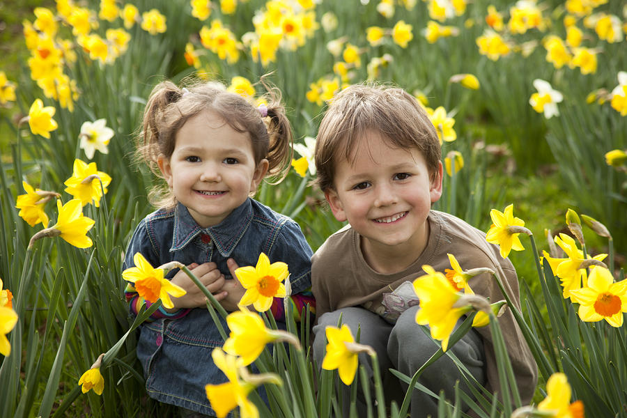 Two small children smiling in a field of daffodils Photograph by Ptaxa