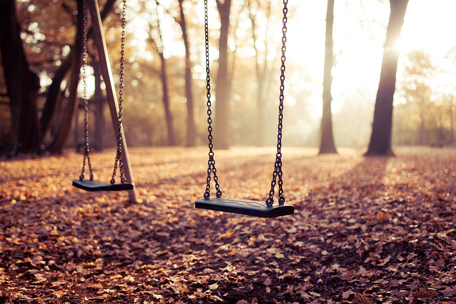 Two swings on playground in sunlight Photograph by Guido Mieth