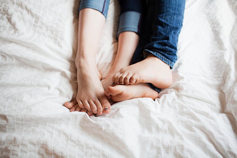 Two teenage girls playing footsie Photograph by Image Source