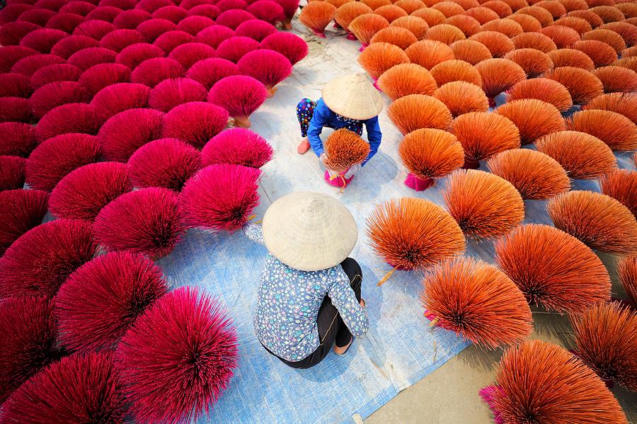 Two Vietnamese women surrounded by bouquets of incense sticks Photograph by Felix Cesare