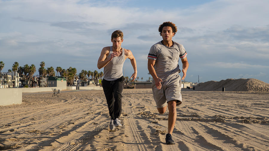 Two young friends jogging at the beach Photograph by Alex Potemkin