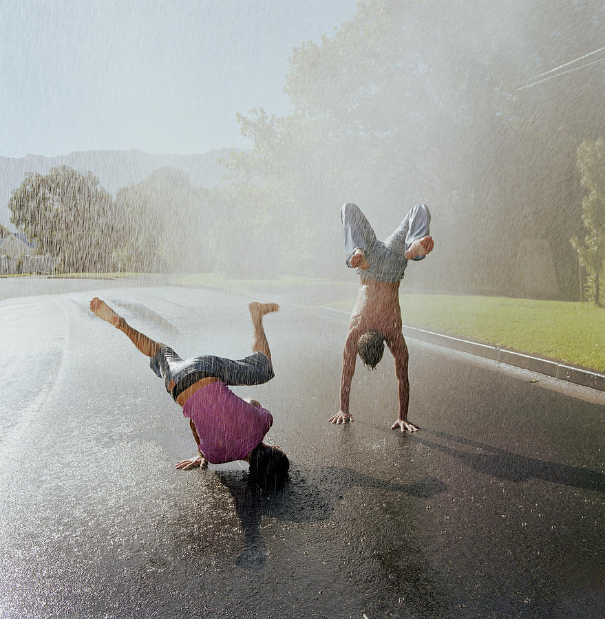 Two young men doing handstands in rain Photograph by Karan Kapoor