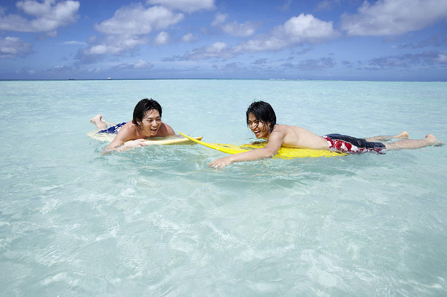 Two Young Men Lie on Surfboards in the Sea, Laughing Photograph by Dex