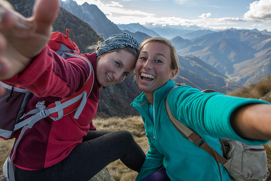 Two young women hiking take selfie portrait at mountain top Photograph by Swissmediavision