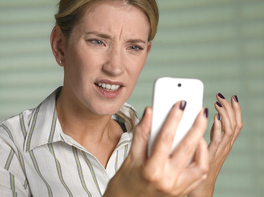 Unhappy woman on smart phone Photograph by Peter Dazeley