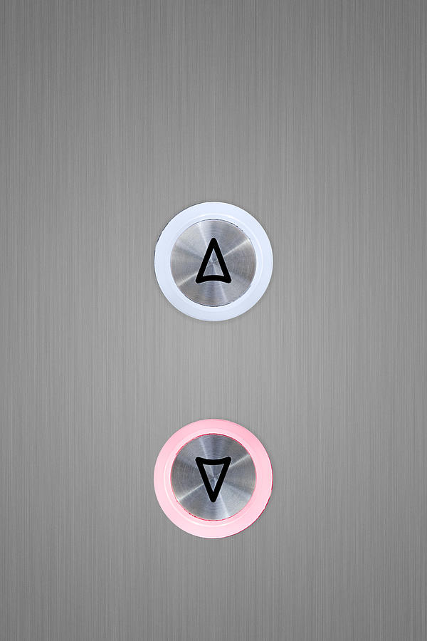 Up and down elevator buttons with down button lit up Photograph by Image Source