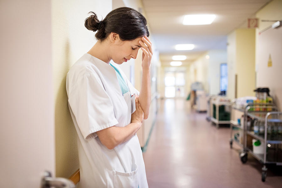 Upset female nurse standing in hospital corridor Photograph by Alvarez