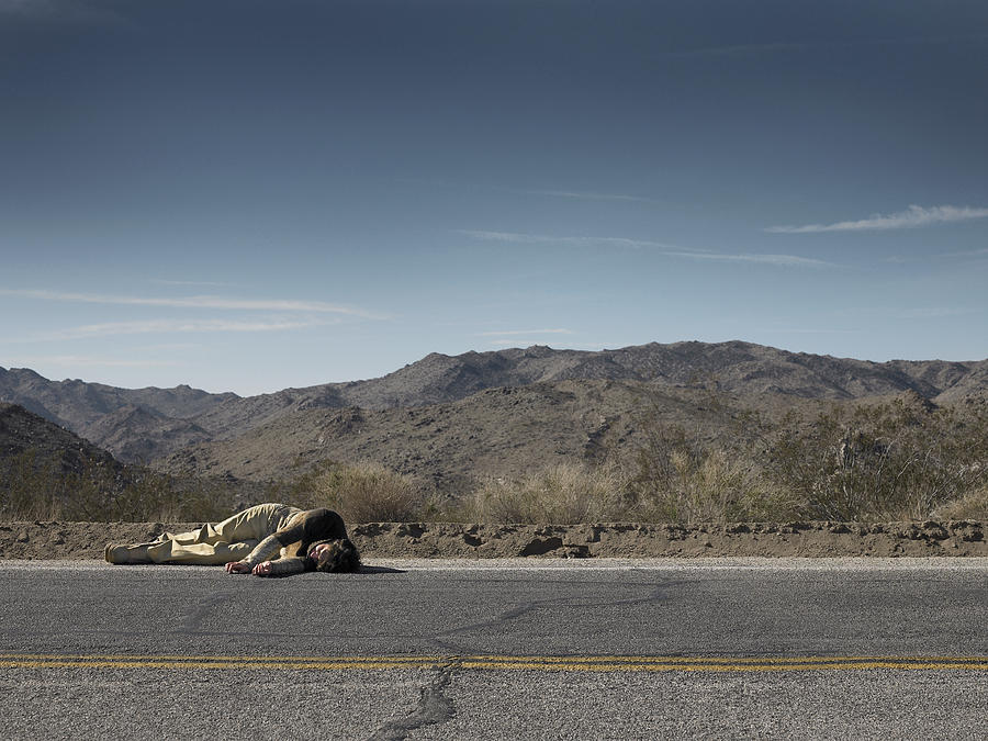 USA, California, Idyllwild, Man lying on roadside in desert landscape Photograph by Thomas Northcut