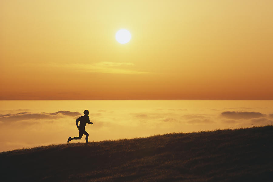 USA, California, silhouette of man running along ridge at sunset Photograph by David Madison