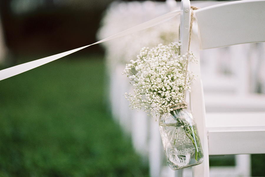 USA, Florida, Orange County, Winter Park, Close-up shot of bunch of babys breath flowers in a mason jar and white ribbon attached to back of white chair Photograph by Benhood