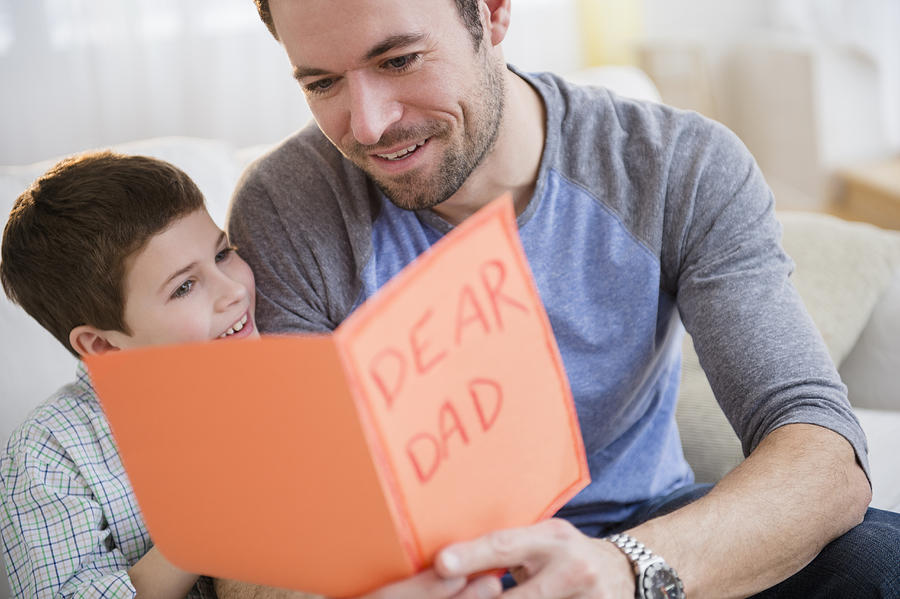 USA, New Jersey, Jersey City, Father and son (8-9) looking at greeting card Photograph by Jamie Grill