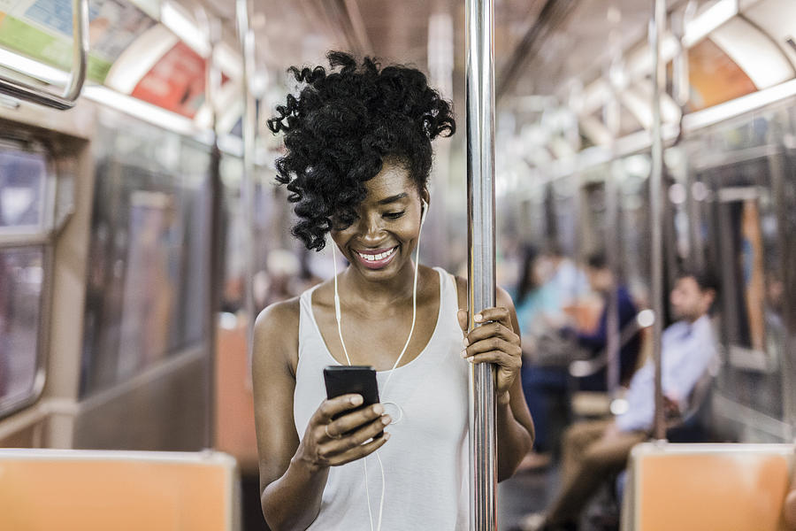 USA, New York City, Manhattan, portrait of happy woman looking at cell phone in underground train Photograph by Westend61