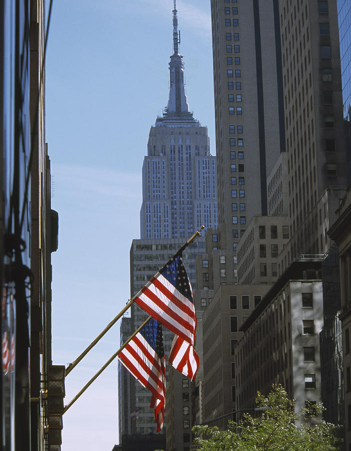 USA, New York, New York City, American flags on building, Empire State Building in background Photograph by Grant Faint