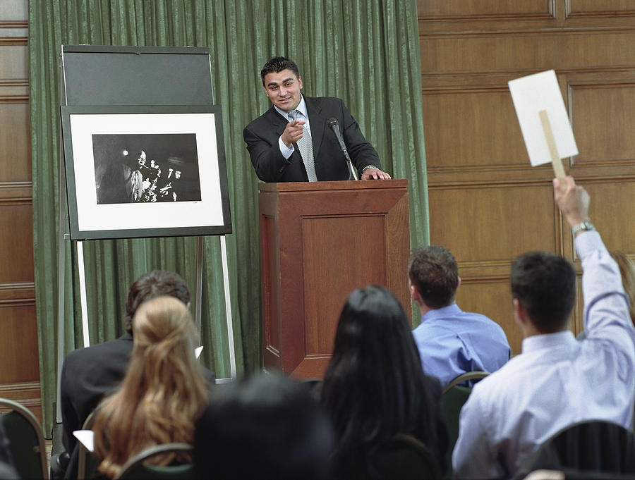 USA, Texas, Dallas, auctioneer taking bid on photograph at auction Photograph by DreamPictures