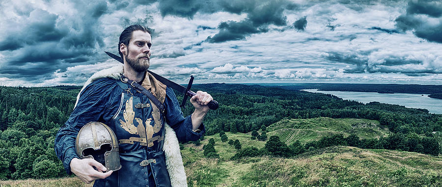 Viking warrior stands on hill overlooking the landscape Photograph by Mikkelwilliam