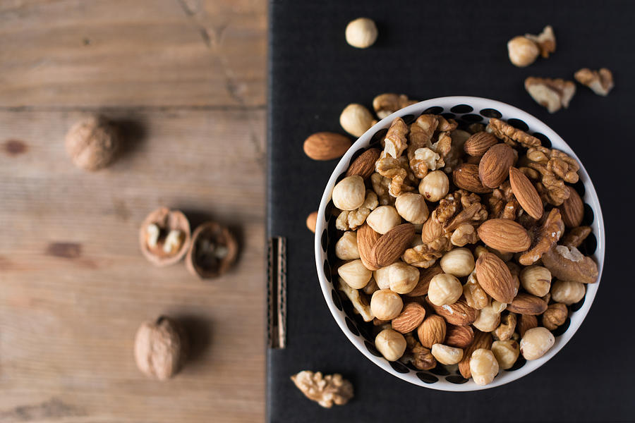 Walnuts, almonds and hazelnuts in a bowl on black background Photograph by Emilija Manevska