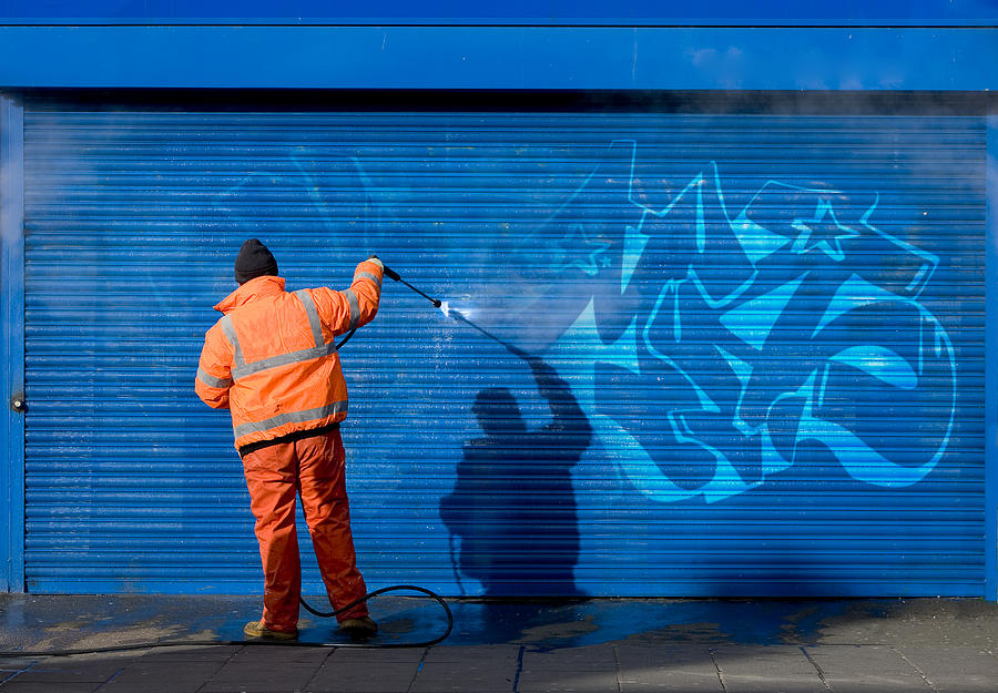 Washing graffiti off a security grill. Photograph by DaveThomasNZ