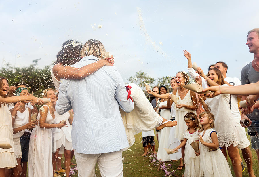 Wedding guests tossing rice at newlyweds, outdoors Photograph by Hans Neleman