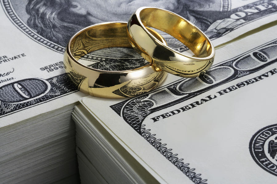 Wedding rings and stack of money Photograph by Ayala_studio