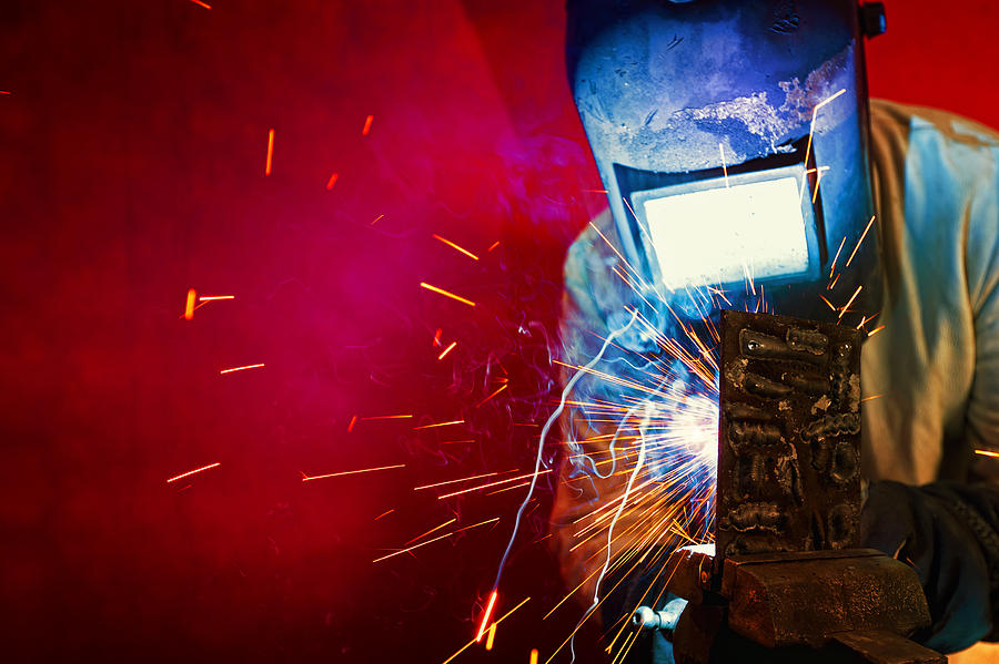 Welder welding, sparks fly. Photograph by Avalon_Studio