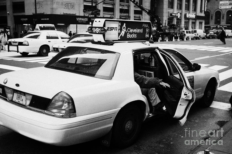 Winter Photograph - white caucasian passenger closes rear door of yellow cab on taxi rank at crosswalk on 7th Avenue by Joe Fox