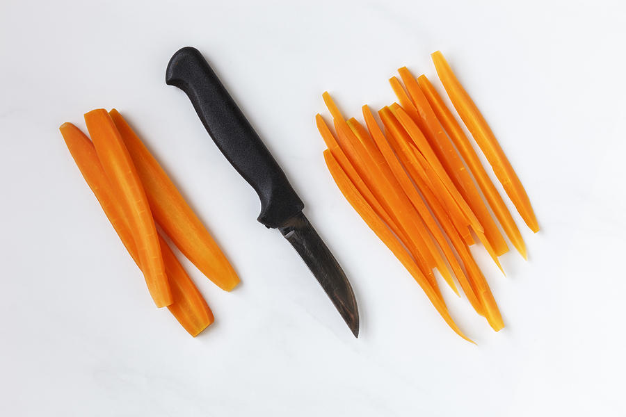 Whole and sliced carrots and kitchen knife on white ground Photograph by Westend61