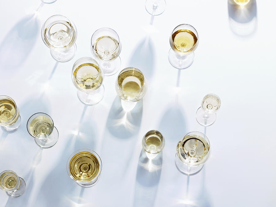 Wine glasses with white wine on white tablecloth Photograph by Maren Caruso