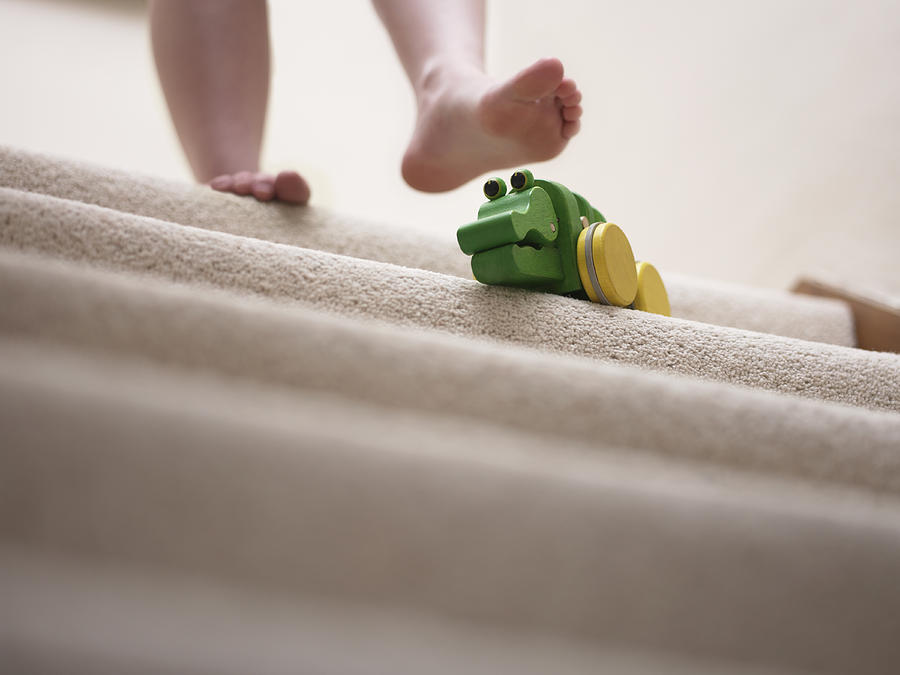 Woman about to slip on toy left on staircase Photograph by Adam Gault