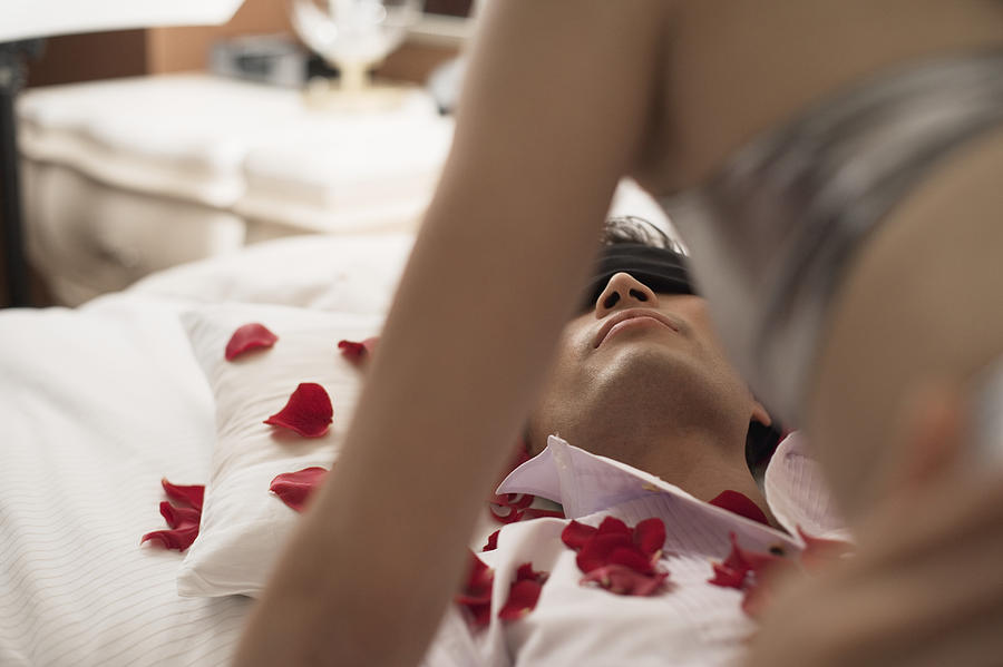Woman Above Blindfolded Man on Bed Photograph by Fuse