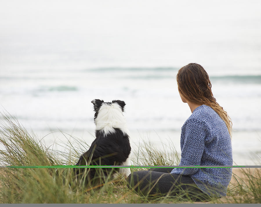Woman and dog look out to sea. Photograph by Dougal Waters
