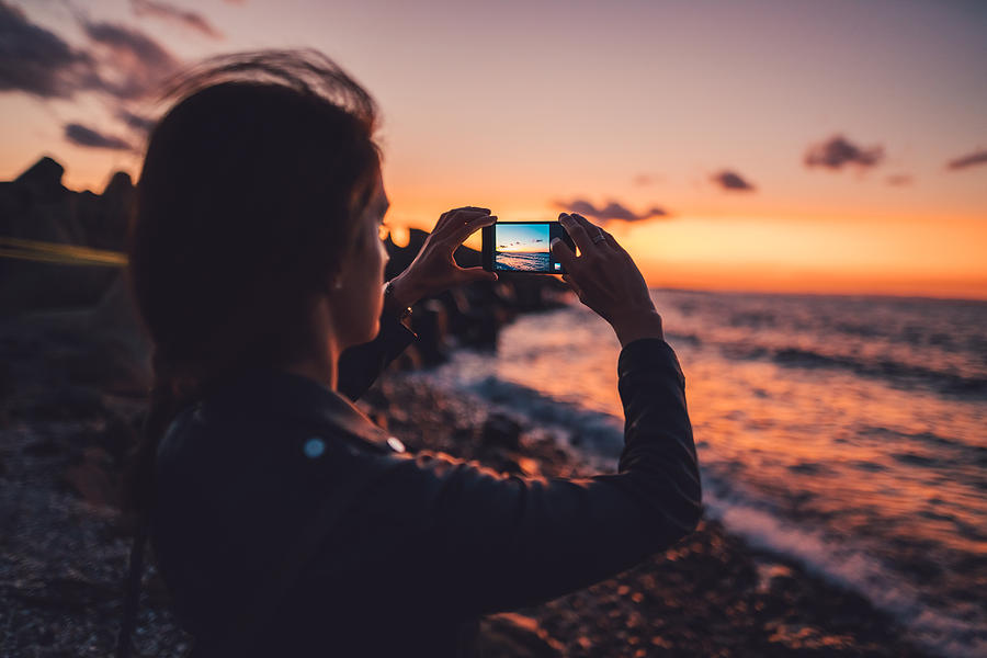 Woman at the beach photographing the sunset Photograph by Martin-dm