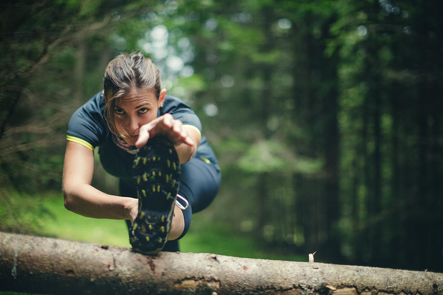 Woman athlete stretching in the forest after running Photograph by Piola666