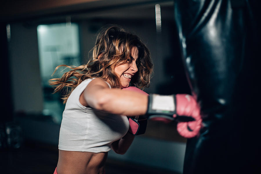 Woman boxer punching a punching bag Photograph by South_agency