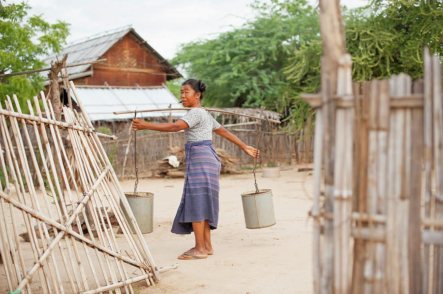 Woman Carrying Buckets With Pole Across Photograph by Cultura Rm Exclusive/yellowdog