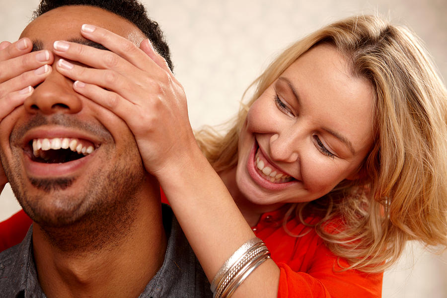 Woman covering boyfriends eyes Photograph by Image Source/Dan Pangbourne