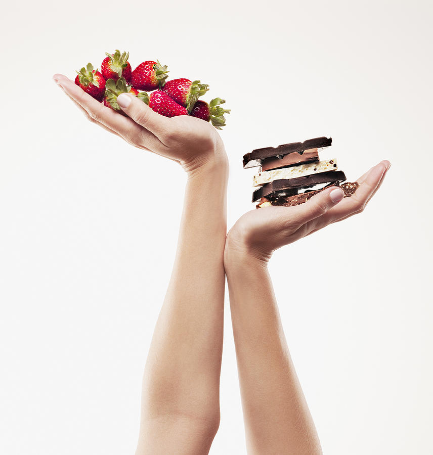 Woman cupping strawberries above chocolate bars Photograph by Chris Ryan