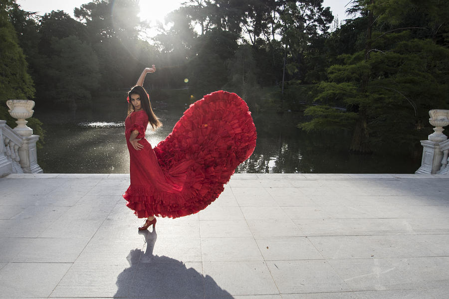 Woman dressed in red dancing flamenco on a terrace in front of a lake Photograph by Westend61