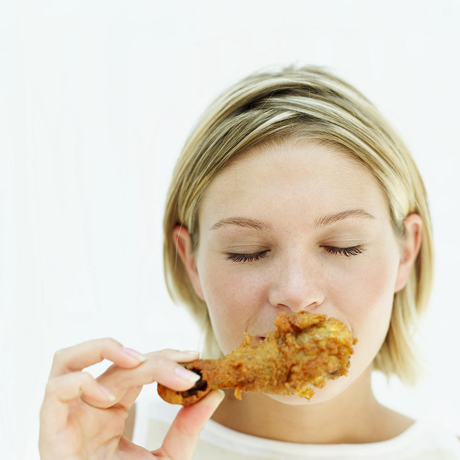 Woman Eating A Fried Chicken Drumstick Photograph by Stockbyte