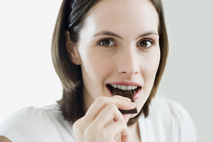 Woman eating chocolate Photograph by Image Source