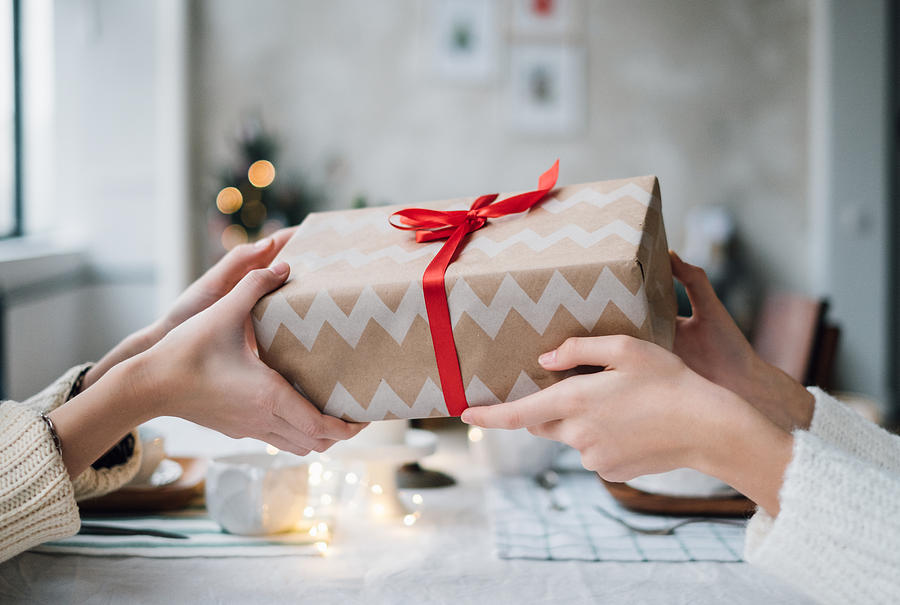Woman giving her friend a wrapped Christmas gift Photograph by Dulin