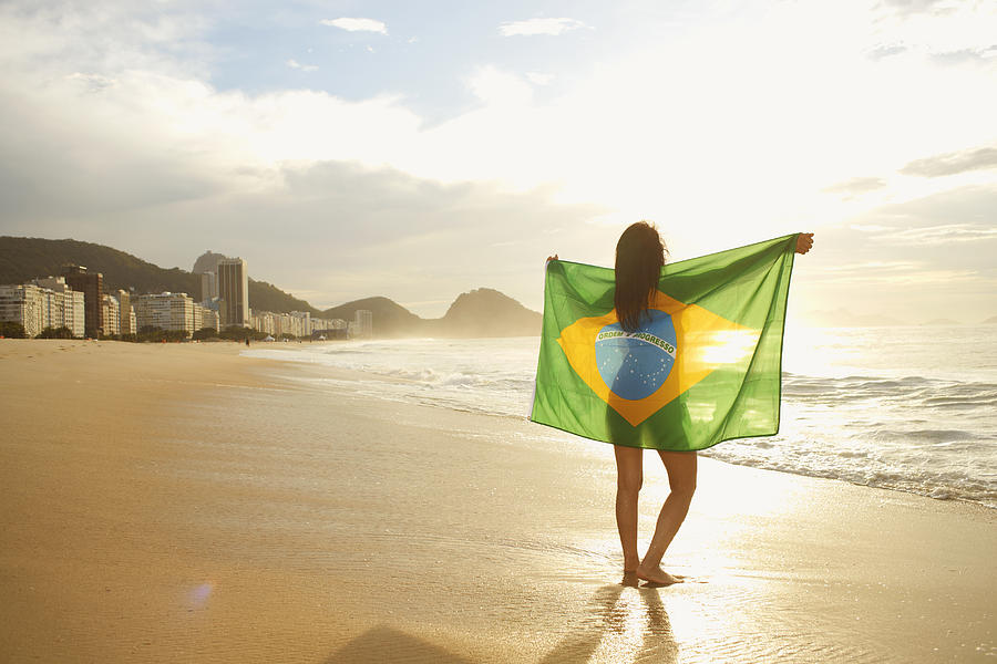 Woman holding Brazilian flag on Copacabana Beach, Rio, Brazil Photograph by Peter Muller