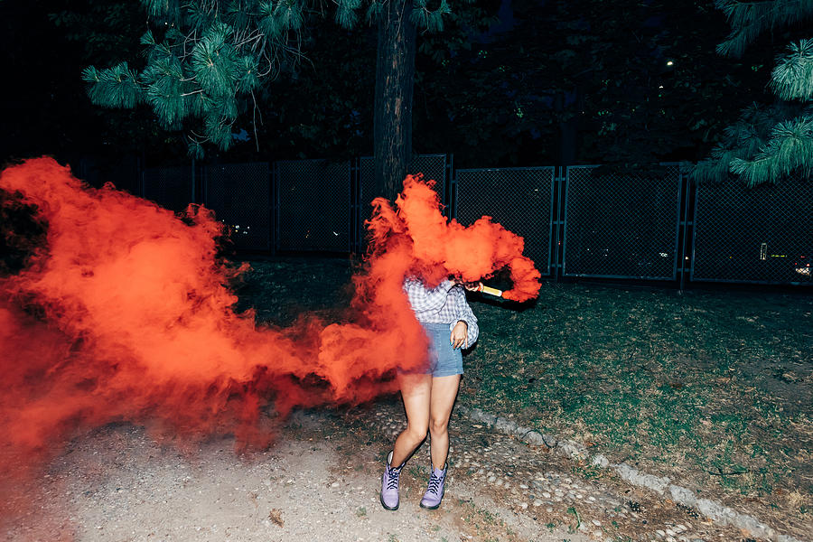 Woman holding flare in park at night Photograph by Eugenio Marongiu