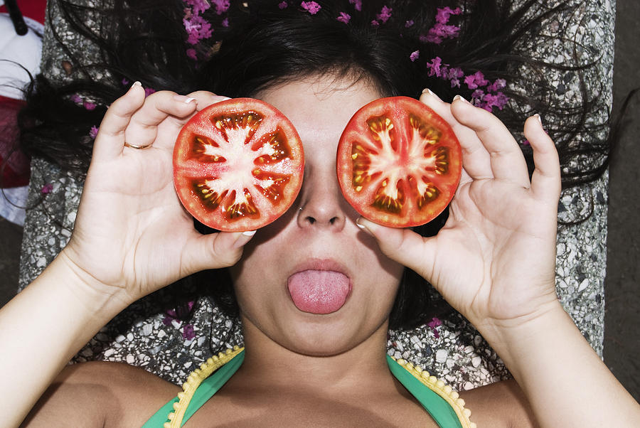 Woman holding tomato slices in front of her eyes with tomato, Santiago, Chile Photograph by Hans Neleman