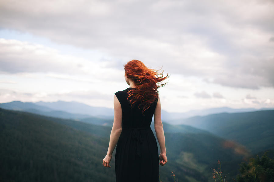 Woman in black dress walking in the mountains and looking at view Photograph by Oleh_Slobodeniuk