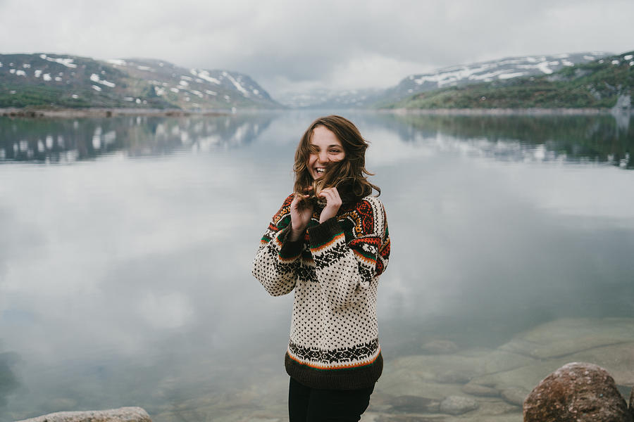 Woman in knitted sweater laughing near the  fjord in Norway Photograph by Oleh_Slobodeniuk